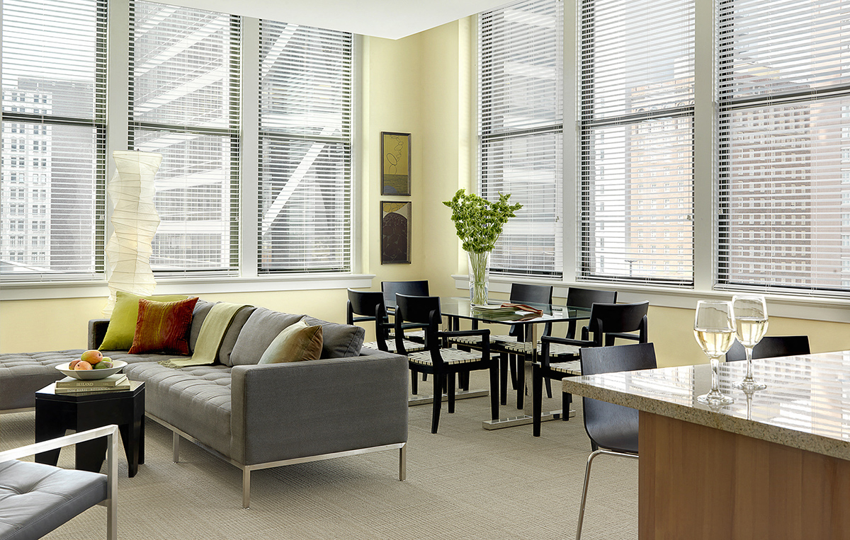 a living room with a couch and a table and chairs in a room with windows